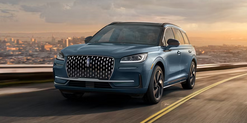 A 2026 Lincoln Corsair SUV drives along a winding road in Houston, Texas, with a city skyline visible in the background at sunset.