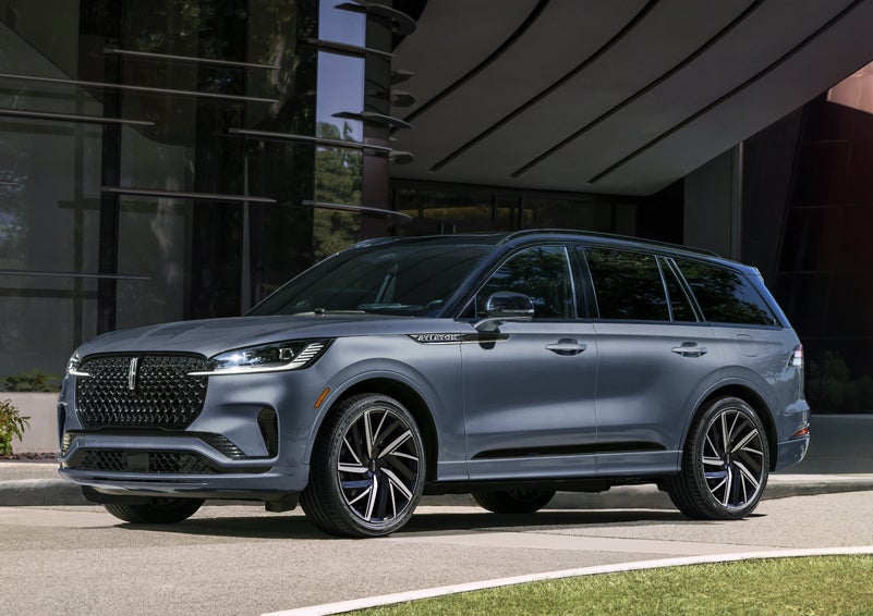 A gray 2025 Lincoln Aviator® SUV is parked outside a modern building showcasing the driver’s side of the vehicle. | Bayway Lincoln in Houston TX