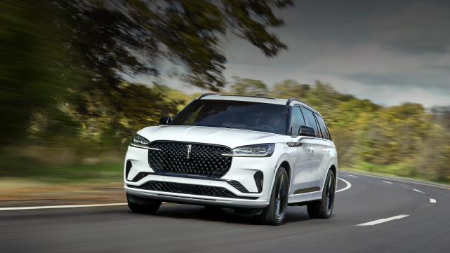 A white 2025 Lincoln Aviator® SUV is being driven down a road lined with trees. | Bayway Lincoln in Houston TX