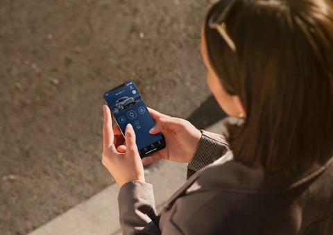 A person is shown interacting with a smartphone to connect to a Lincoln vehicle via the Lincoln Way® App.