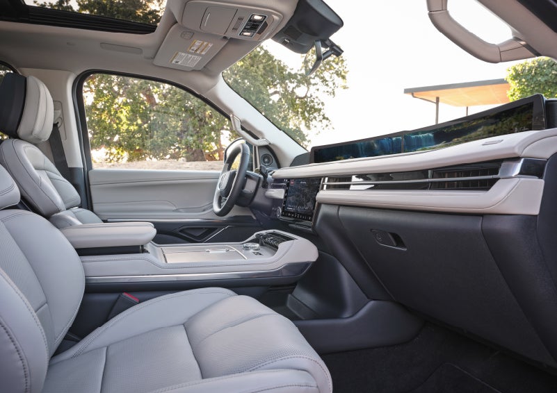 A smartphone is charging on the wireless charging pad* in the front center console cubby.