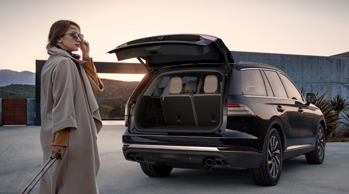 A woman approaches a 2026 Lincoln Aviator® SUV with its rear liftgate open. | Bayway Lincoln in Houston TX