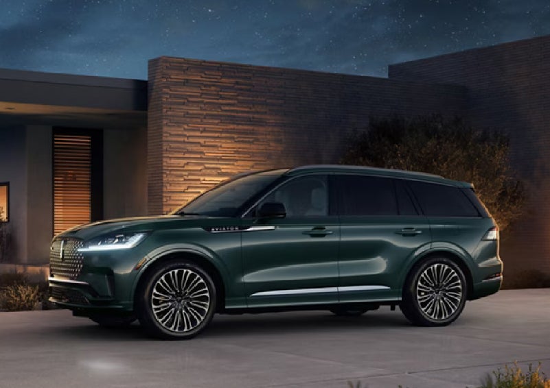 A green 2027 Lincoln Aviator® SUV is parked outside a contemporary home. | Bayway Lincoln in Houston TX
