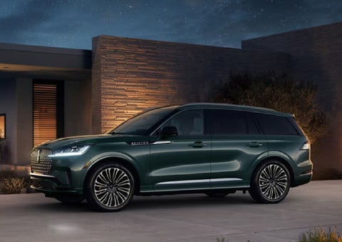A green 2027 Lincoln Aviator® SUV is parked outside a contemporary home. | Bayway Lincoln in Houston TX