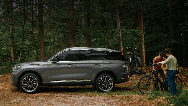 A father and son load e-bikes on a bike rack attached to a 2027 Lincoln Aviator® SUV. | Bayway Lincoln in Houston TX